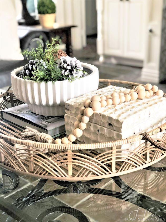 coffee table vignette for winter with rattan tray, bowl with pinecones and natural balls