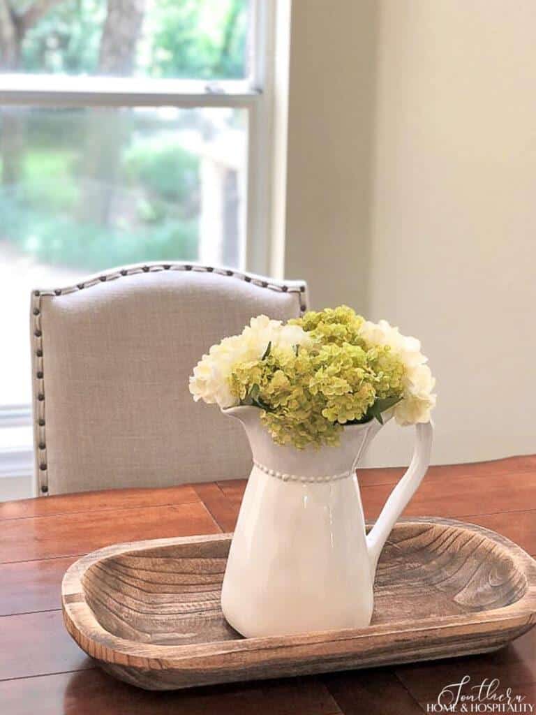 Green and white hydrangeas in white pitcher on kitchen table
