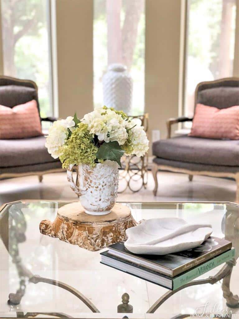Green and white hydrangeas in white pitcher on living room coffee table
