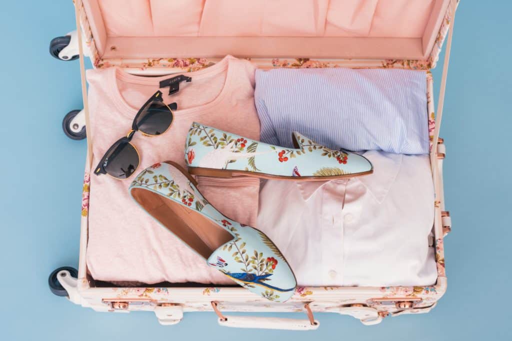 Clothes, shoes, and sunglasses in pink suitcase