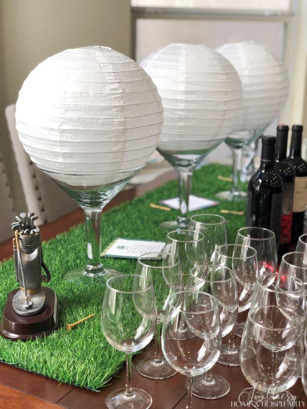 Golf theme party wine station with golf ball centerpieces and artificial grass runner