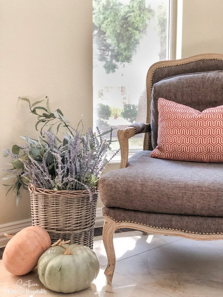 French basket with heirloom pumpkins beside Bergere chair