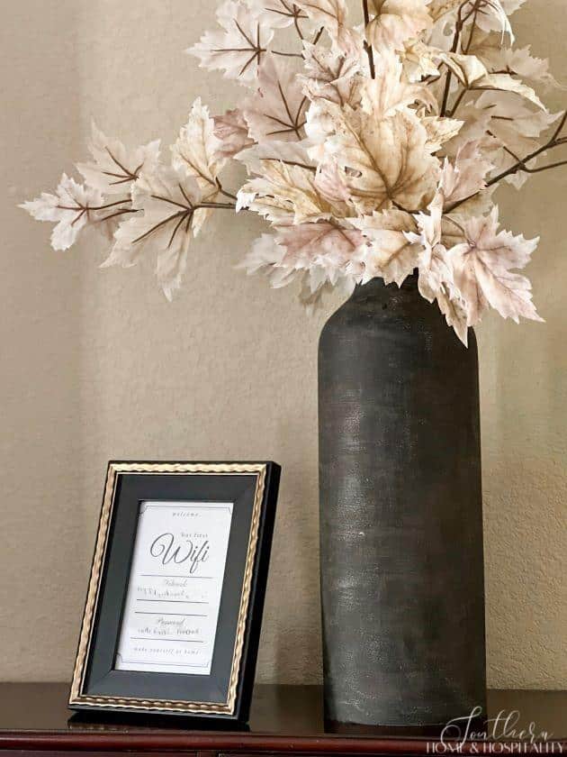 wifi code in frame and vase of leaves decorating guest bedroom