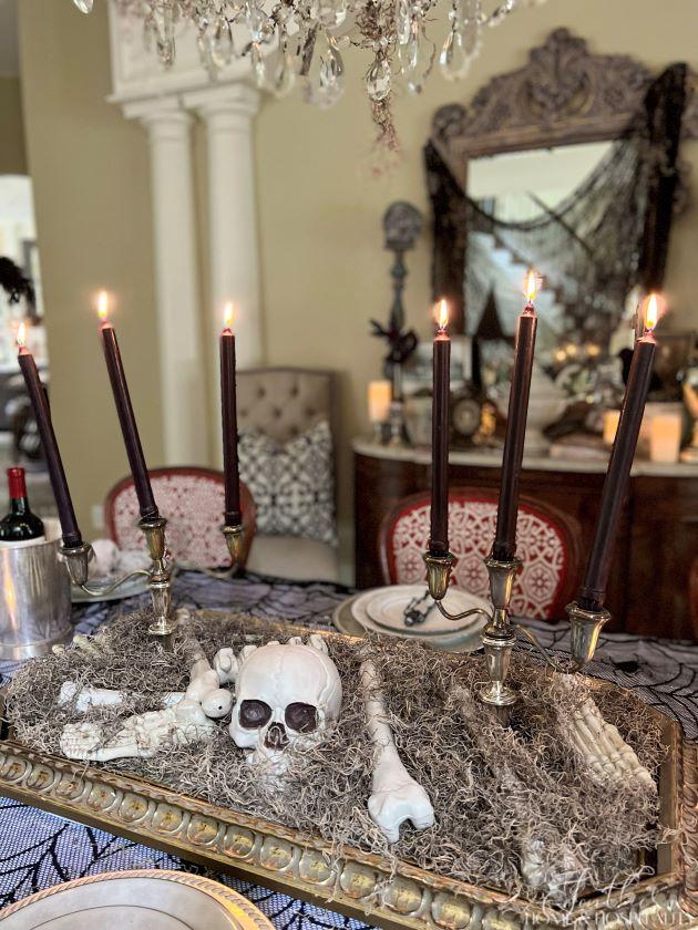 spooky chic gothic halloween dining centerpiece with skeleton moss and candles