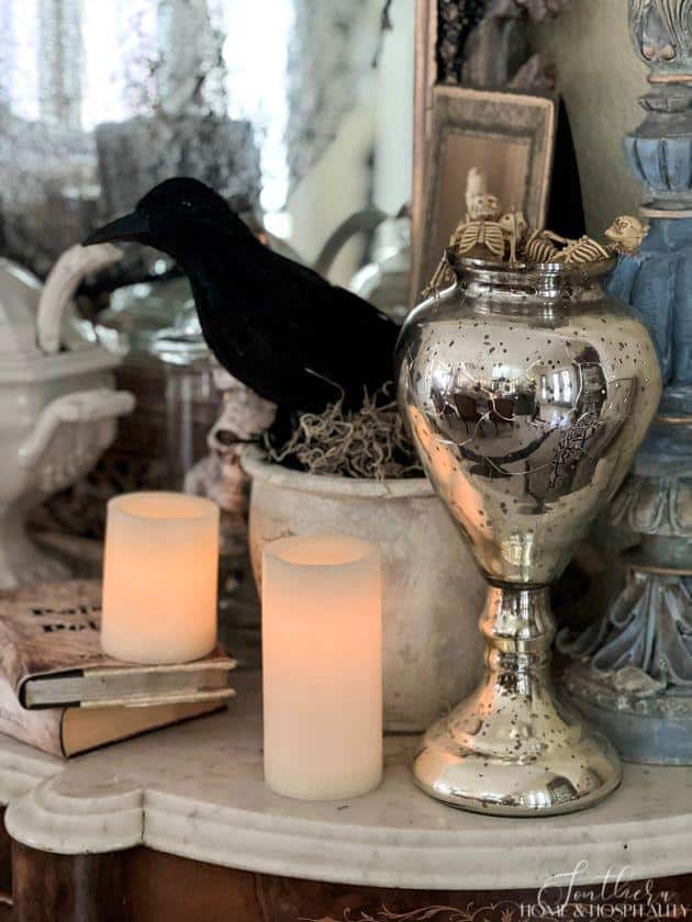 creepy chic Halloween vignette with mercury glass, crow, candles, skeletons