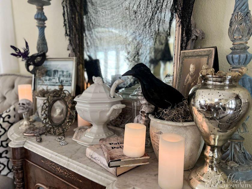 spooky chic southern gothic Halloween dining room sideboard with vintage photos, books, silver