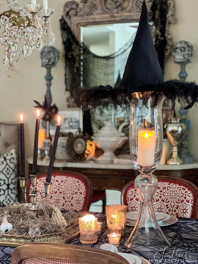 spooky chic southern gothic Halloween dining tablescape with witch hat and candles