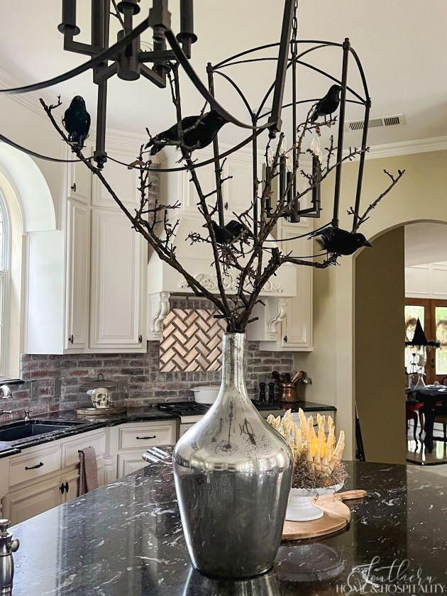 Halloween decorations on kitchen island with crows on tree branches