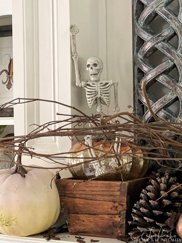 Skeleton on pumpkin on mantel