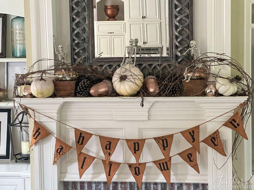 Halloween mantel with pennant banner, skeletons, pumpkins, acorns, and pinecones