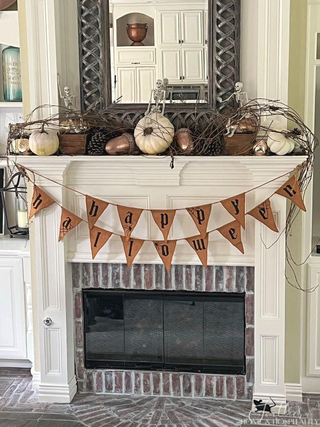 Halloween mantel with pennant banner, skeletons, pumpkins, acorns, and pinecones