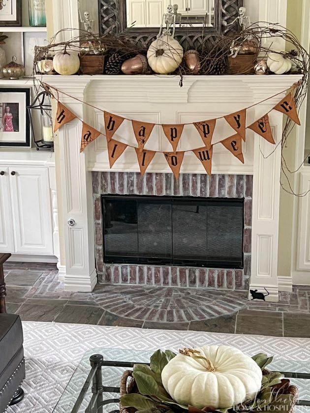 Halloween mantel with pennant banner, skeletons, pumpkins, acorns, and pinecones
