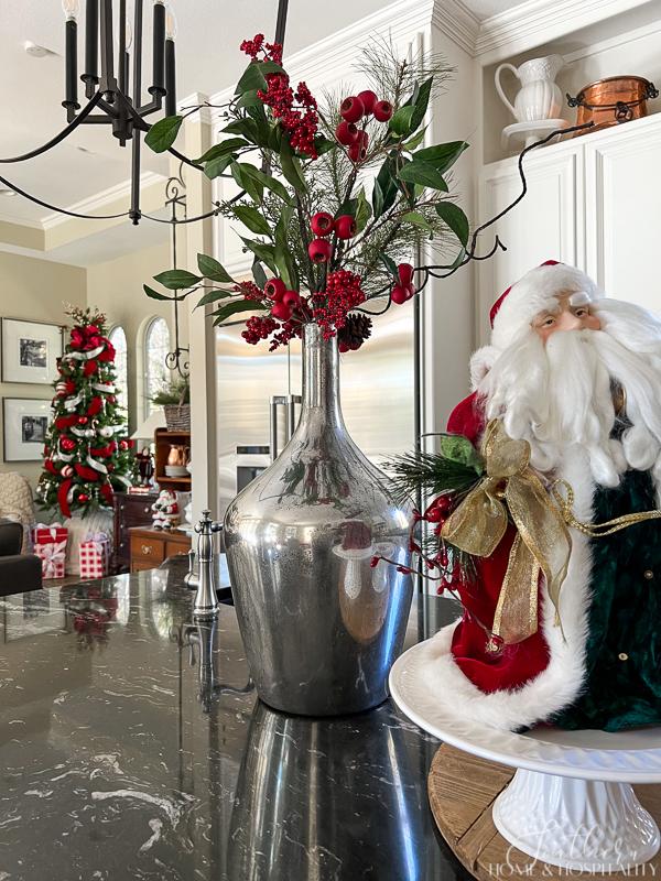 mercury glass vase with greenery and red berries, vintage Santa, black kitchen counters, red and white Christmas tree