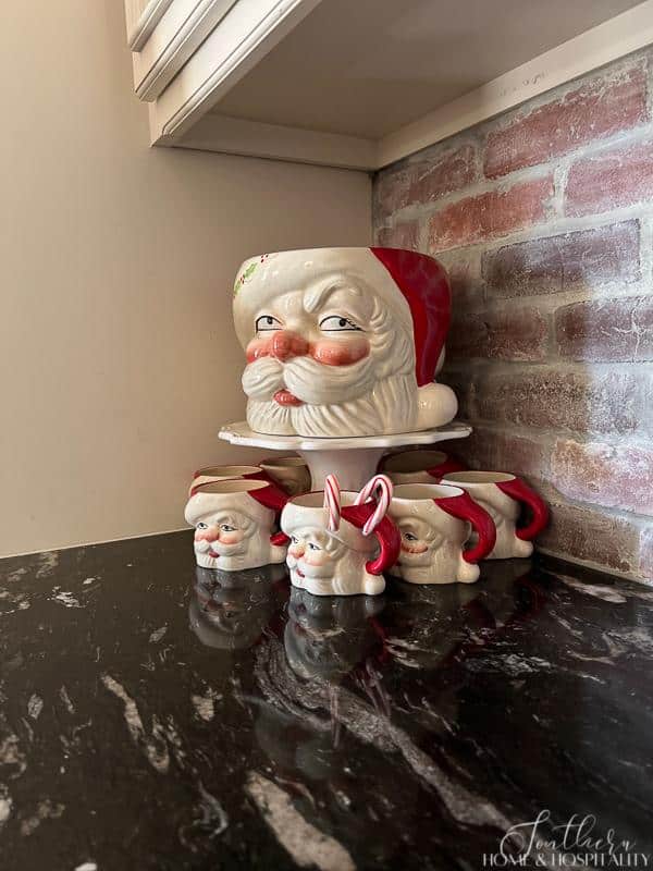 Santa mugs and punch bowl, brick backsplash, black kitchen counters