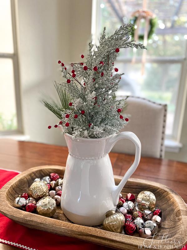 Christmas dough bowl arrangement, white pitcher with flocked tree and red berries, mercury glass ornaments and bells