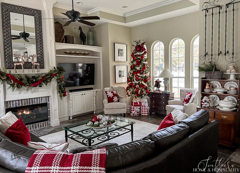 red and white Christmas decor, red and white pillows, red and white throw blanket, hutch with ironstone and santa mugs, fireplace mantel with garland, red and white Christmas tree