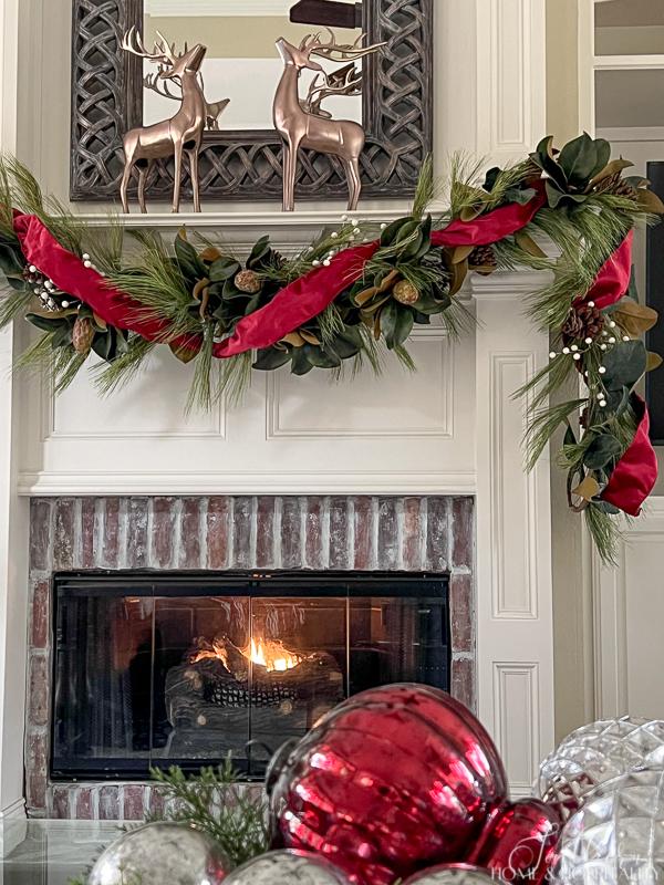 magnolia and pine Christmas garland on fireplace mantel, copper deer 