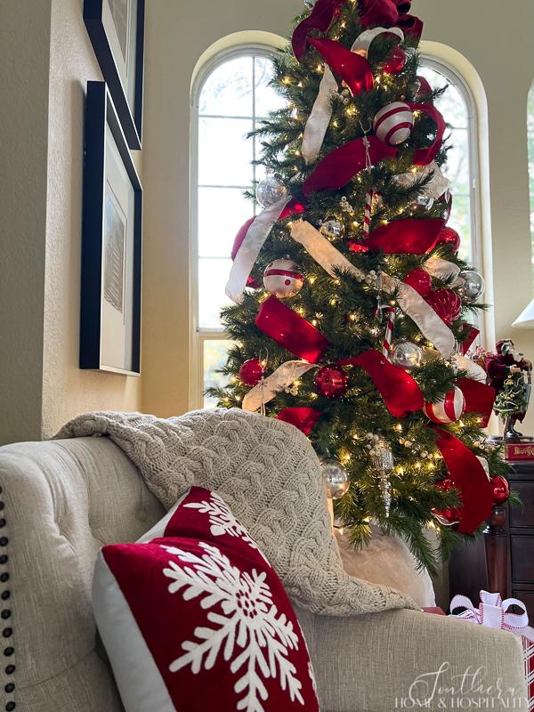 red and white ornaments and ribbon on Christmas tree, snowflake pillow, cable knit throw