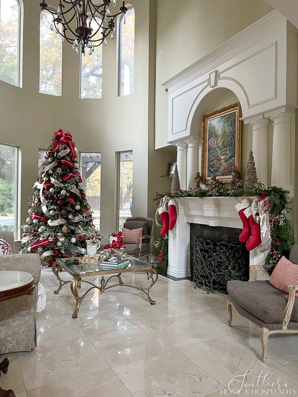 traditional living room with Christmas tree and garland on fireplace with red and white decorations