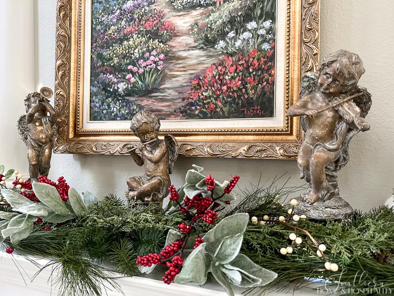 Christmas angel statues with red and white berries and greenery