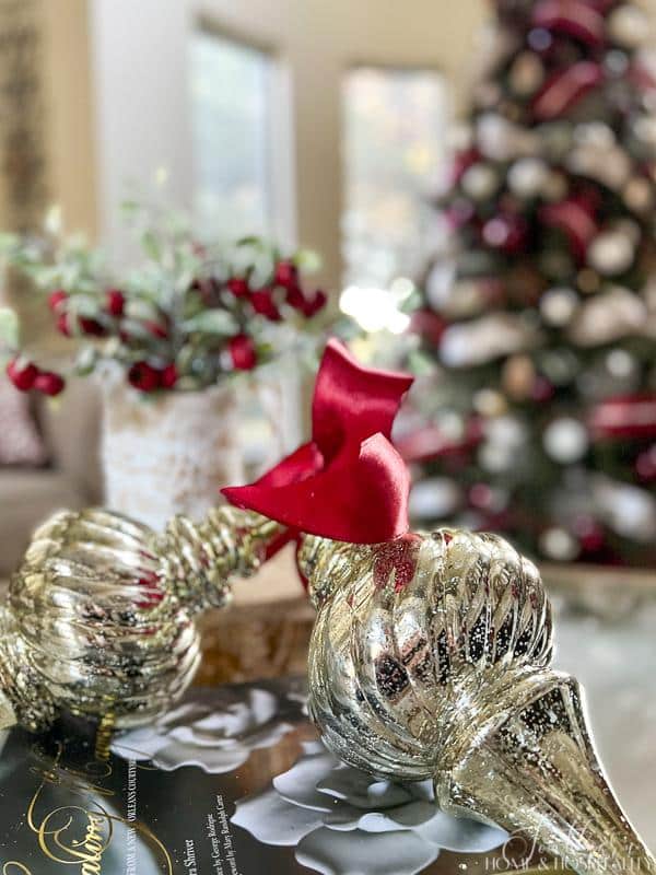 oversized mercury glass finial ornaments tied with red ribbon on coffee table