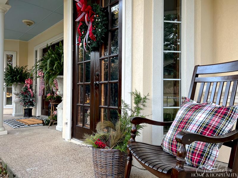 front porch decorated for Christmas rocker with plaid pillow large ferns lantern