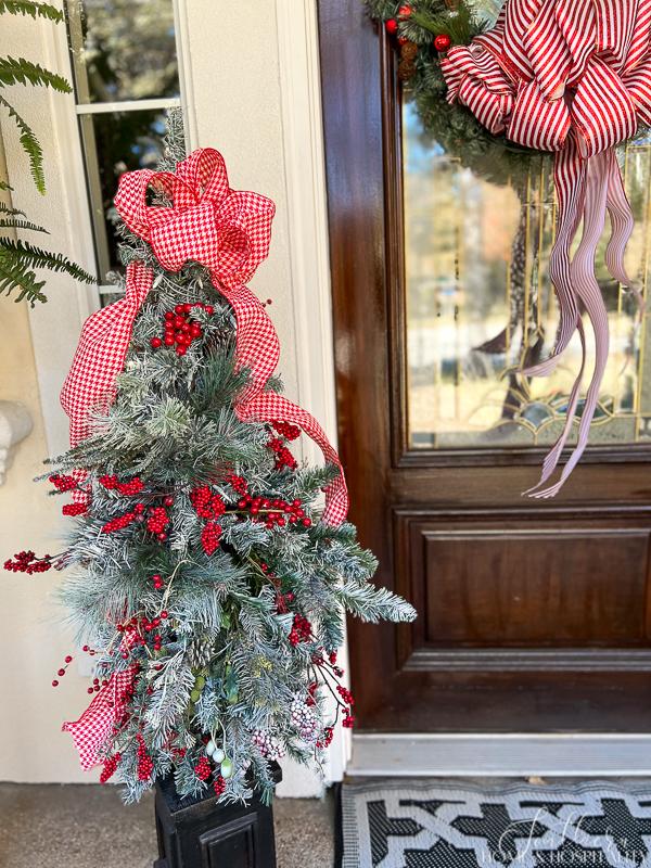 Christmas tree on porch with red bow and red berries