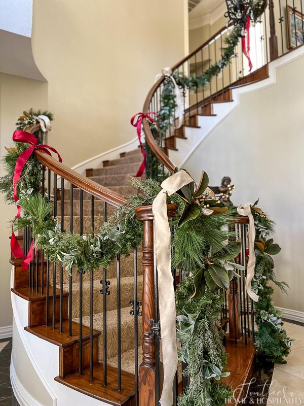 Staircase with Christmas garland of mixed greenery, pine, magnolia, cedar, berries, and ribbon