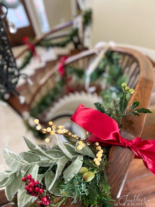 Staircase banister with Christmas garland and white and red berries, eucalyptus, and red ribbon
