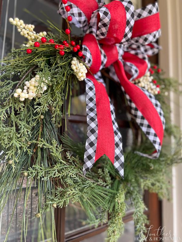 Christmas wreath with piner, cedar, red and white berries, red and black and white gingham bow