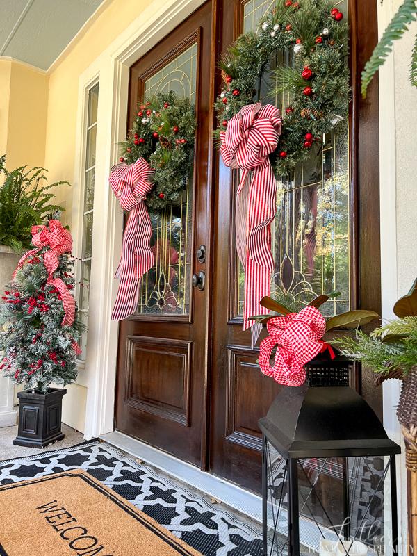 Christmas wreaths on double doors with red and white ribbons
