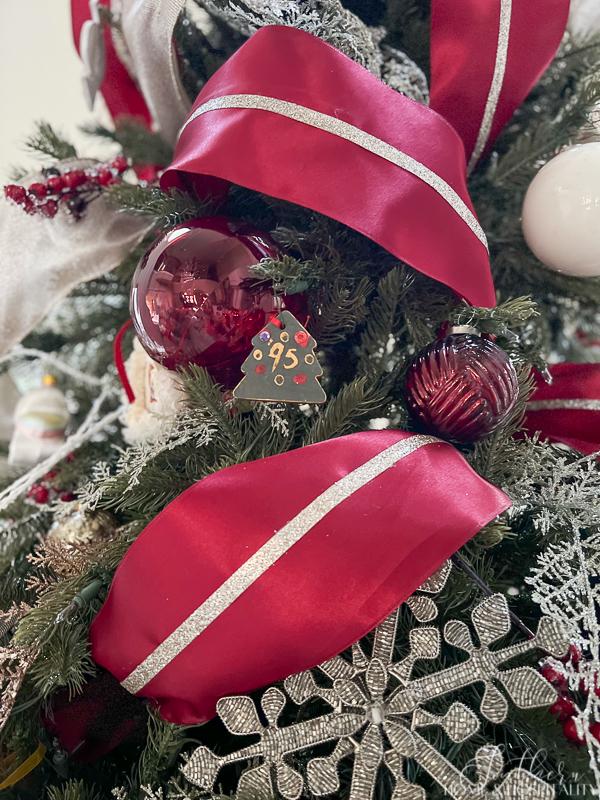 Christmas tree with red and champagne ribbon and red, silver, and white ornaments