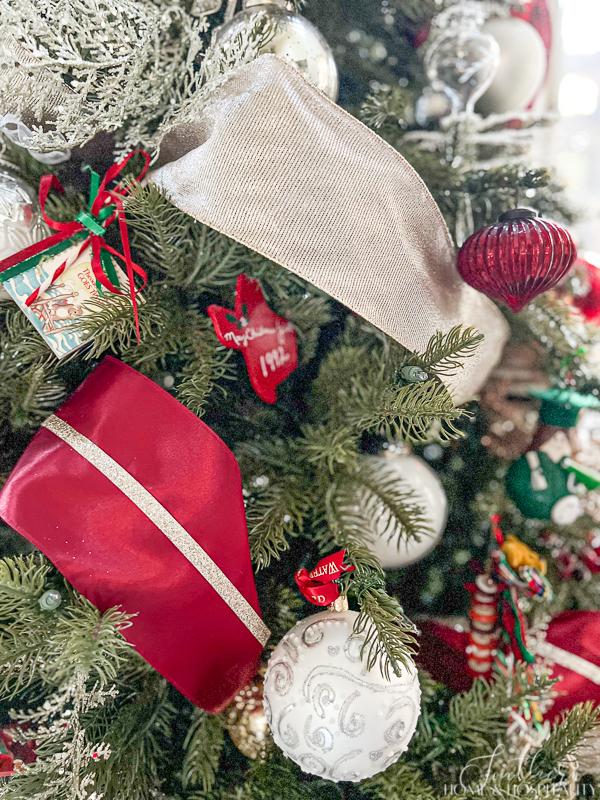 Christmas tree with red and champagne ribbon and red, silver, and white ornaments