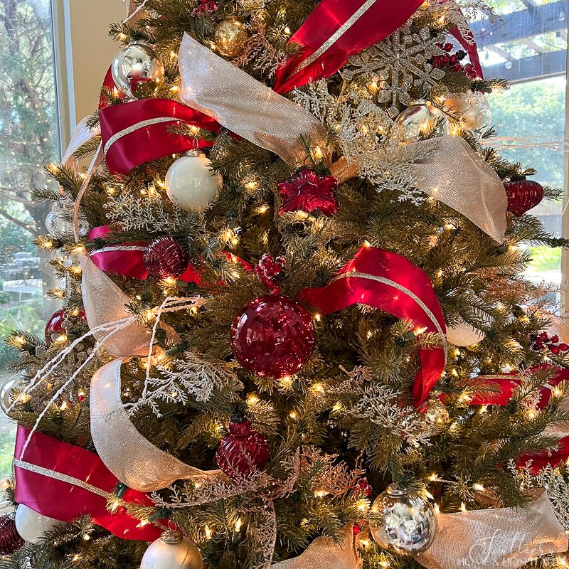 Christmas tree with red and champagne ribbon and red, silver, and white ornaments