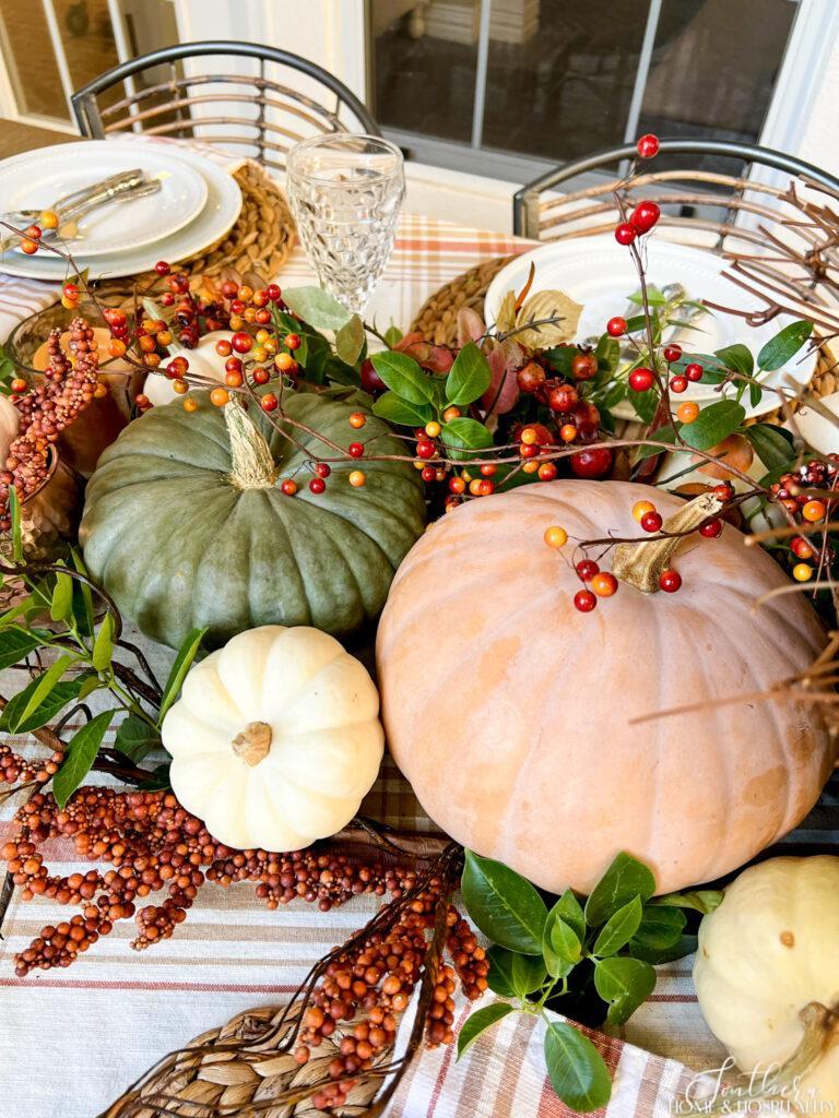 Heirloom Pumpkins, fall colored berry garland, and greenery in a dining table centerpiece