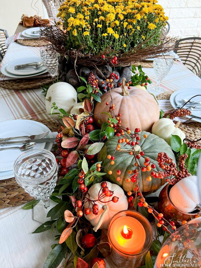 Pumpkins, mums, and candles on outdoor dining table