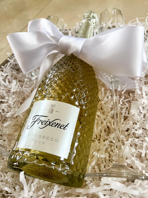 Prosecco bottle with white ribbon and champagne flutes