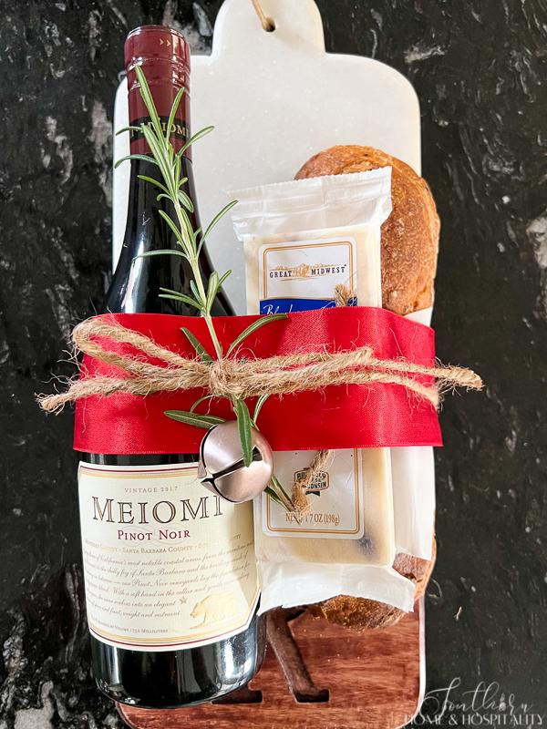 wine cheese and bread on cheese board tied with ribbon
