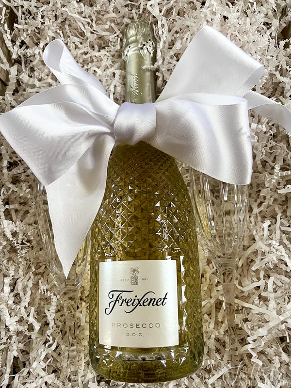 Prosecco bottle with white ribbon and champagne flutes