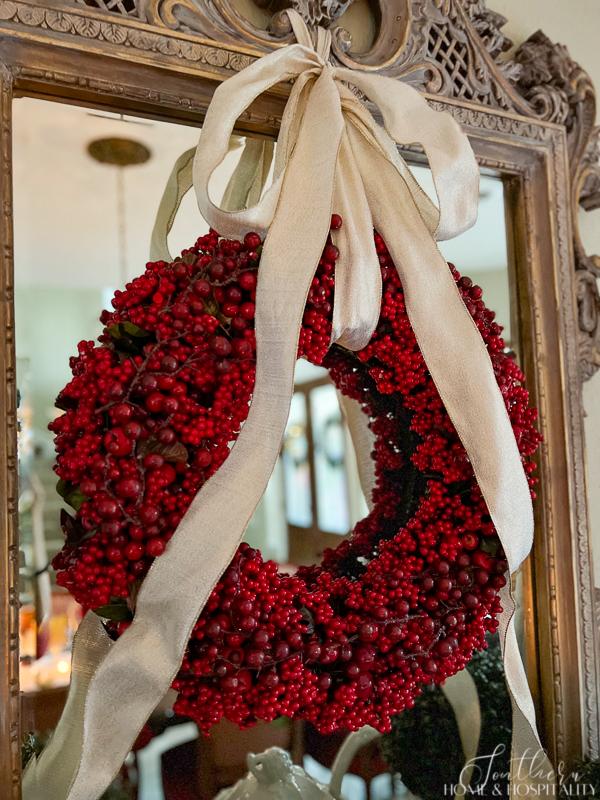 red berry wreath with bow on mirror