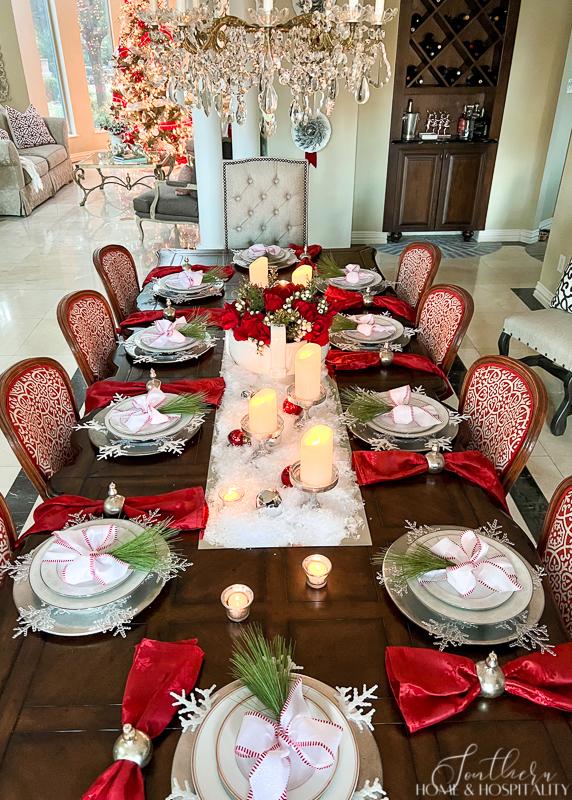 red and white Christmas table red roses in white bowl red wreath snow candles