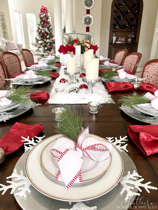 red and white Christmas table red roses in white bowl red wreath snow candles bow around plate