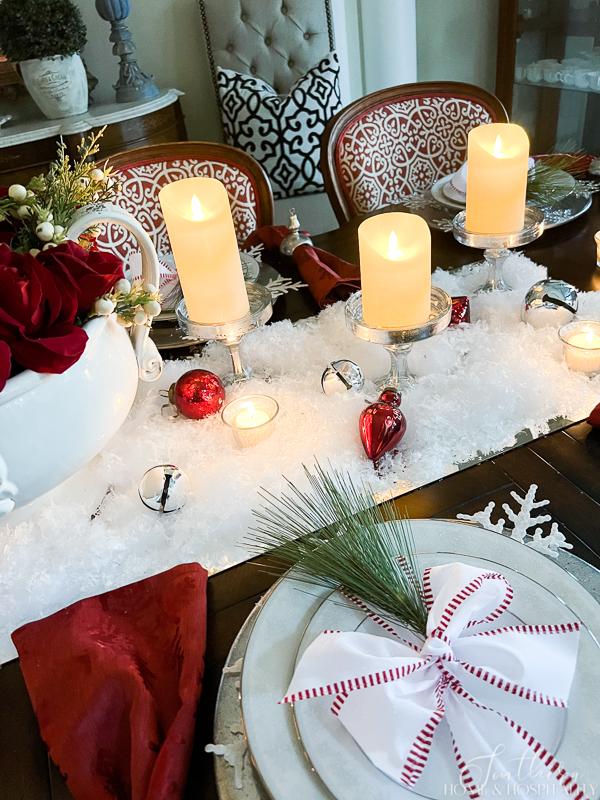 red and white Christmas table red roses in white bowl red wreath snow candles flameless candles