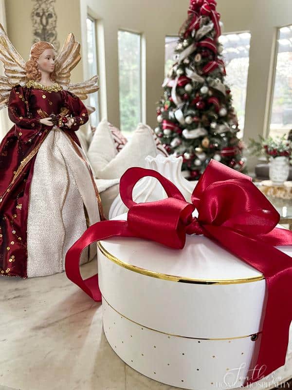 white round gift with red bow and Christmas angel