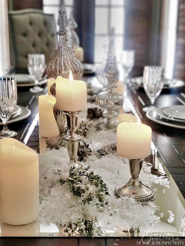 Winter table centerpiece with a mirror, snow, and candles