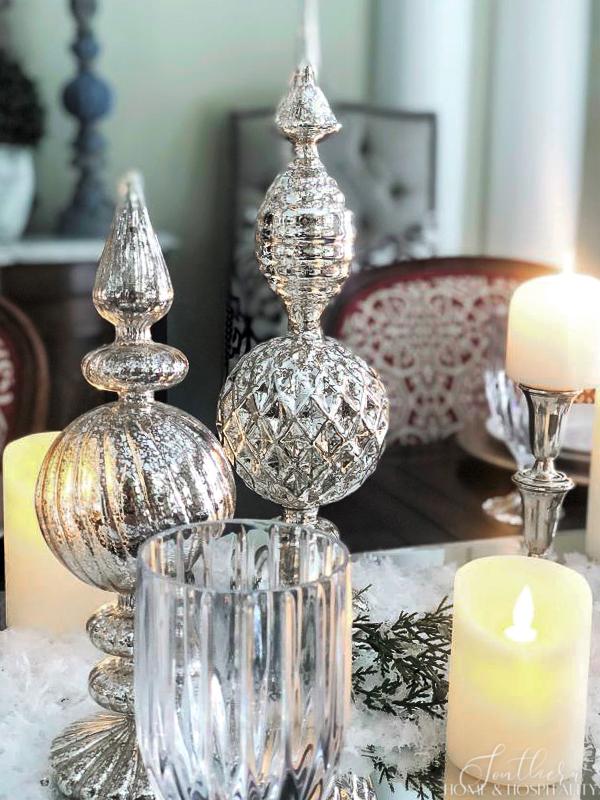 Mercury glass finials, candles, and silver candlesticks in a winter tablescape