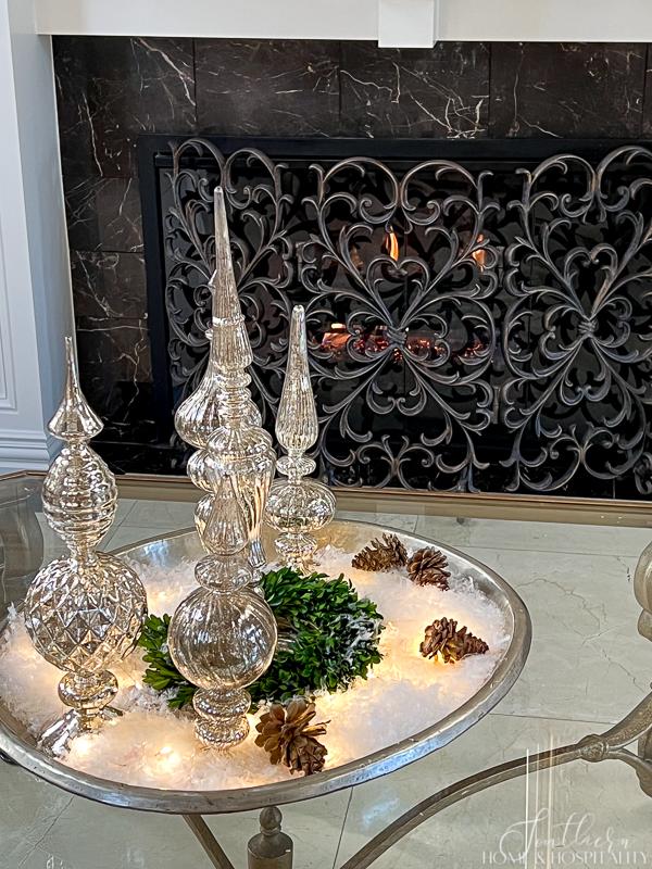 winter coffee table decor, mercury glass finials in silver tray with snow, pinecones, boxwood, fairy lights