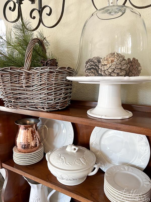 ironstone dishes, winter greenery and pinecones in French basket, pinecones under cloche