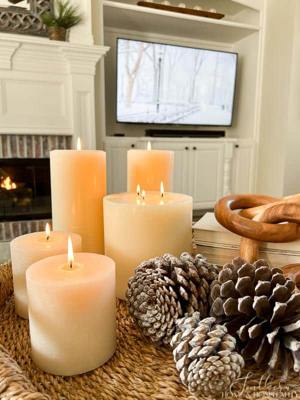 Candles in winter vignette on coffee table, winter scene on tv, fire in fireplace