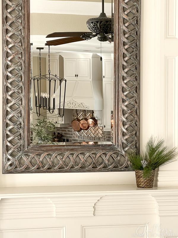 fireplace mantel with winter pine greenery, mirror, French country kitchen with copper pots, large kitchen pendants